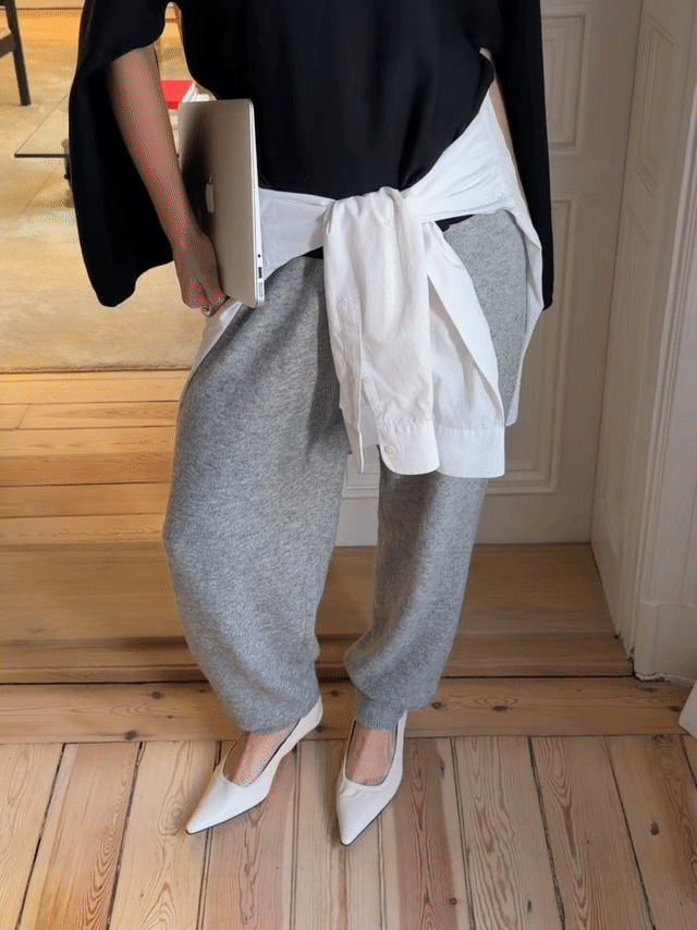 Johanna Lager styles her grey knitted sweatpants with white pumps, a white shirt tied around the waist and a black long sleeved t-shirt